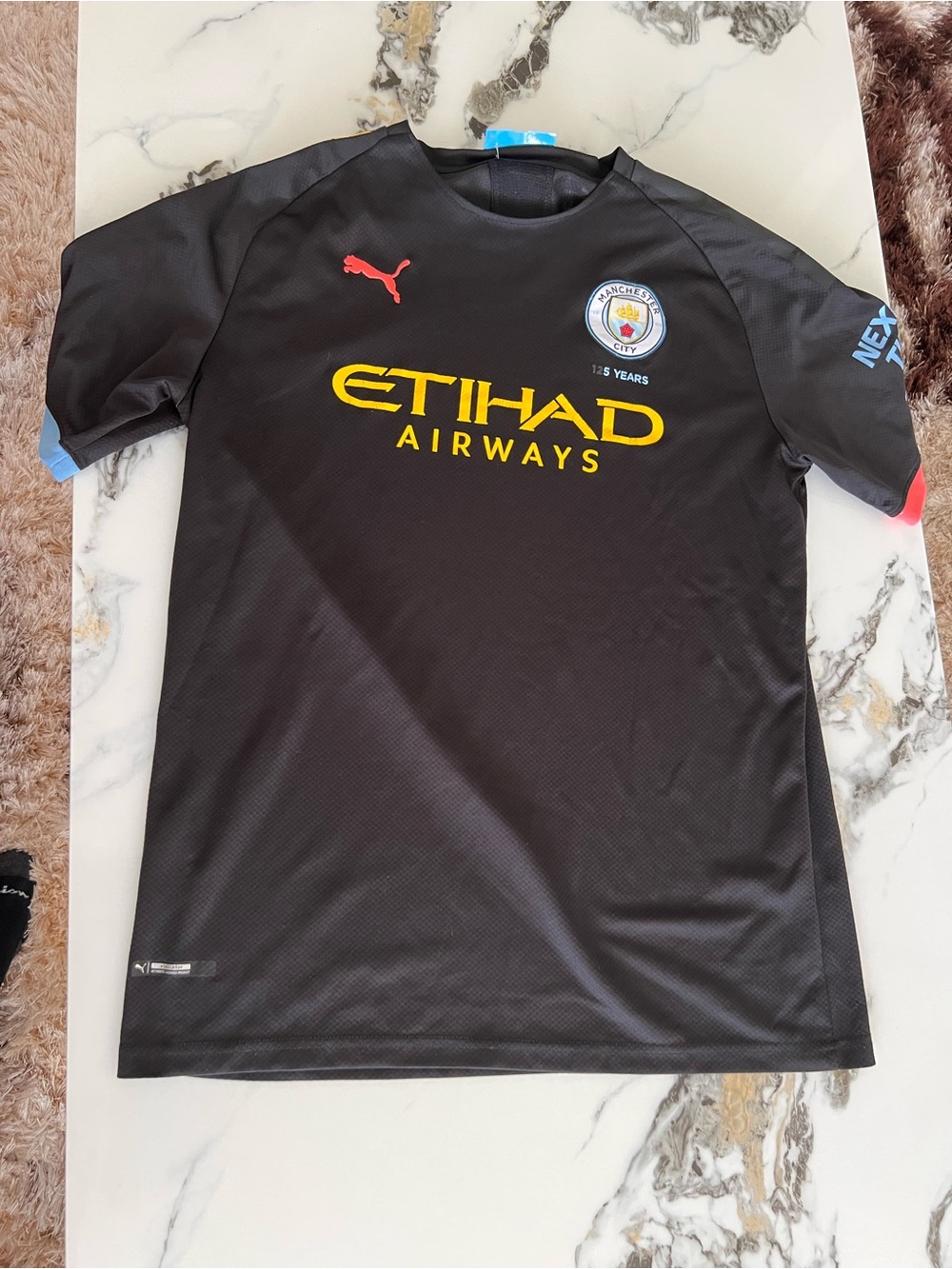 Puma Kids Black Football Shirt with Yellow Etihad Logo and Red Puma